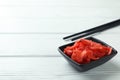 Bowl with red pickled ginger and chopsticks on white wooden background Royalty Free Stock Photo