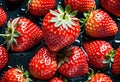 A bowl of red strawberries, a seedless fruit, with green leaves on a table Royalty Free Stock Photo