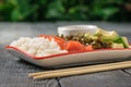 Bowl with rice, avocado, seaweed and salmon on a wooden table on a background of green vegetation