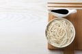 Bowl of rice cooked noodles and soy sauce served on white wooden table, flat lay. Space for text Royalty Free Stock Photo