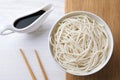 Bowl of rice cooked noodles and soy sauce served on white wooden table, flat lay Royalty Free Stock Photo