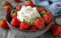 A bowl of ripe, juicy strawberries topped with a dollop of whipped cream, ready to be enjoyed on a textured surface. Royalty Free Stock Photo