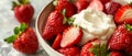 A bowl of ripe, juicy strawberries topped with a dollop of whipped cream, ready to be enjoyed on a textured surface. Royalty Free Stock Photo