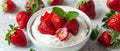 A bowl of ripe, juicy strawberries topped with a dollop of whipped cream, ready to be enjoyed on a textured surface. Royalty Free Stock Photo