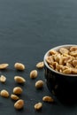 Bowl with roasted and salted peanuts on a slate with copy space Royalty Free Stock Photo