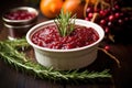 bowl of ruby-red cranberry sauce beside sprigs of rosemary