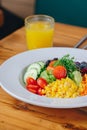 A bowl of salad with a glass of orange juice on a wooden table Royalty Free Stock Photo