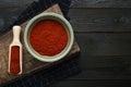 Bowl and scoop of aromatic paprika on black wooden table, flat lay. Space for text Royalty Free Stock Photo