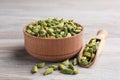 Bowl and scoop with dry cardamom pods on wooden table, closeup Royalty Free Stock Photo
