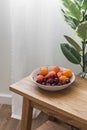 A bowl with seasonal summer fruits and berries on a wooden oak bench in a cozy living room Royalty Free Stock Photo