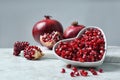 Bowl with seeds and pomegranates on table against grey