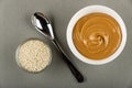 Bowl with sesame seeds, spoon, white bowl with peanut butter on table. Top view Royalty Free Stock Photo