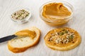 Sesame, sunflower seeds, pumpkin seeds, bowl with peanut butter, knife with peanut butter on slice of bread, sandwich on wooden Royalty Free Stock Photo