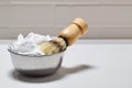 Bowl with shaving foam and brush on white background in bathroom