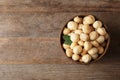 Bowl with shelled organic Macadamia nuts and space for text on wooden background Royalty Free Stock Photo