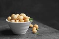 Bowl with shelled organic Macadamia nuts on table against dark background. Royalty Free Stock Photo