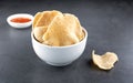 A bowl of shrimp crackers and sauce on a gray background. Kerupuk udang - shrimp chips popular in Southeast Asia.