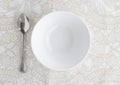 Bowl and silver spoon empty on patterned table cloth - Top view