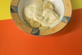 Bowl of sliced banana and yoghurt in a bowl on bright orange and Royalty Free Stock Photo