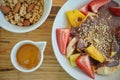 Bowl of sliced fruits and berries with chocolate souse and crushed walnuts with granola and orange juice