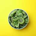 Bowl with slices of kiwi on color background, top view. Royalty Free Stock Photo