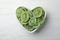 Bowl with slices of kiwi on wooden background, top view. Royalty Free Stock Photo