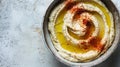 A bowl of smooth, creamy garleek hummus, drizzled with golden olive oil and sprinkled with spices, on a rustic grey Royalty Free Stock Photo