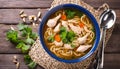 A bowl of soup with noodles, chicken, and carrots