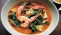 A bowl of soup with shrimp, spinach, and other vegetables