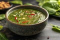 Bowl of spinach soup with chil pods and almonds