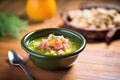 bowl of split pea soup with ham garnish on wooden table