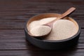 Bowl and spoon with active dry yeast on wooden table, closeup. Space for text Royalty Free Stock Photo