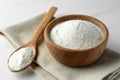 Bowl and spoon of agar-agar powder on white table, closeup