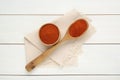 Bowl and spoon with aromatic paprika powder on white wooden table, flat lay Royalty Free Stock Photo