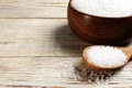 Bowl and spoon with natural sea salt on white wooden table, closeup. Space for text Royalty Free Stock Photo