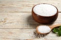 Bowl and spoon with natural sea salt on white wooden table. Space for text Royalty Free Stock Photo