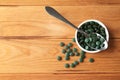 Bowl and spoon with spirulina tablets on wooden table Royalty Free Stock Photo