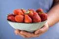 A bowl of strawberries held in one hand by a girl in pastel blue clothes Royalty Free Stock Photo
