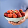 A bowl of strawberries held in one hand by a girl in pastel blue clothes Royalty Free Stock Photo