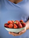 A bowl of strawberries held in one hand by a girl in pastel blue clothes Royalty Free Stock Photo