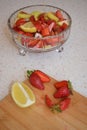 A bowl of strawberries, a lemon and brown sugar.