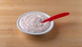 Bowl of strawberry rhubarb yogurt on a wood table