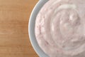 Bowl of strawberry rhubarb yogurt on a wood table