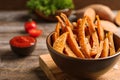 Bowl with sweet potato fries on wooden table Royalty Free Stock Photo