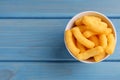 Bowl of tasty cheesy corn puffs on blue wooden table, top view. Space for text Royalty Free Stock Photo