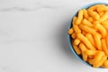 Bowl of tasty cheesy corn puffs on white marble table, top view. Space for text Royalty Free Stock Photo