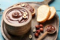 Bowl of tasty chocolate paste with hazelnuts on light blue wooden table, space for text Royalty Free Stock Photo