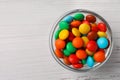 Bowl with tasty colorful candies on white wooden table, top view. Space for text Royalty Free Stock Photo