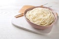 Bowl of tasty cooked rice noodles and chopsticks on white wooden table. Space for text Royalty Free Stock Photo