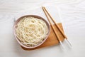 Bowl of tasty cooked rice noodles and chopsticks on white wooden table, top view Royalty Free Stock Photo